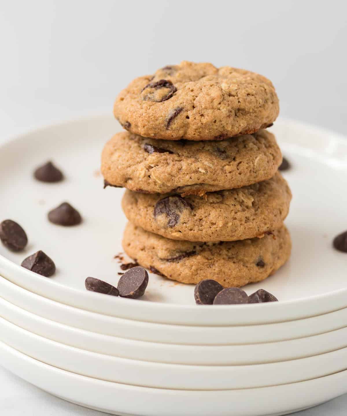 four whole wheat chocolate chip cookies stacked on a white plate