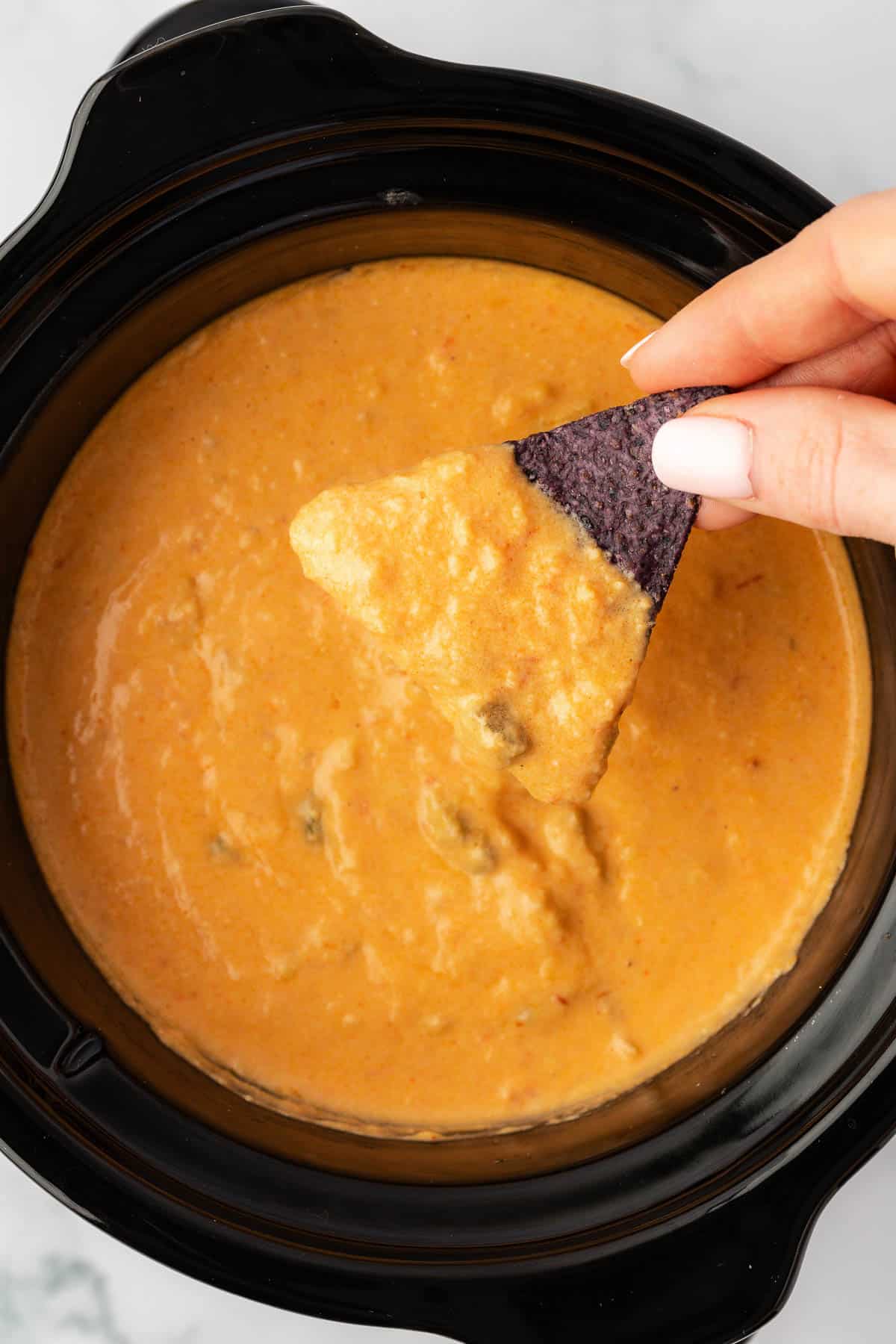 chip being dipped into queso dip