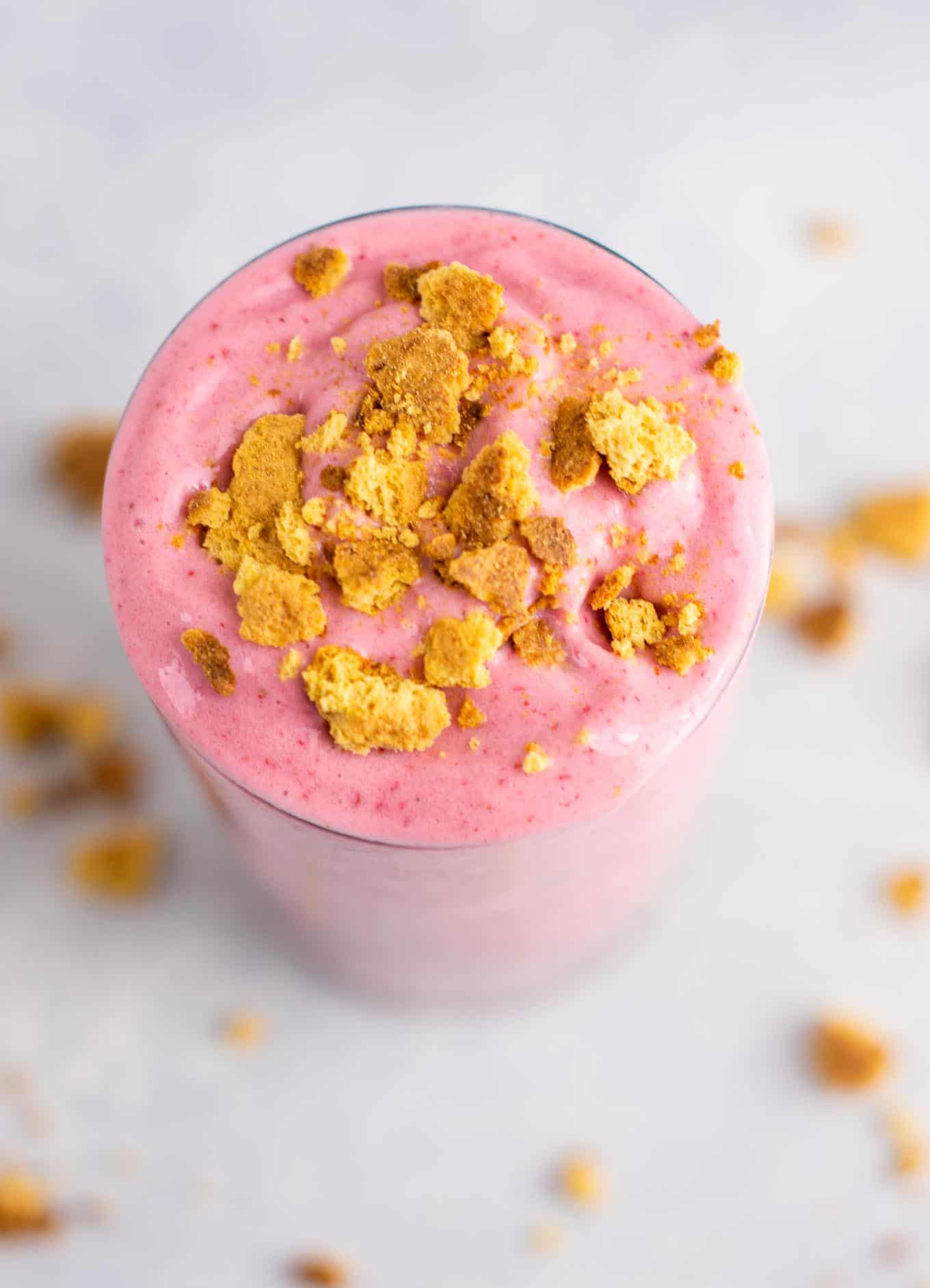 strawberry cheesecake smoothie in a glass with crushed graham cracker on top