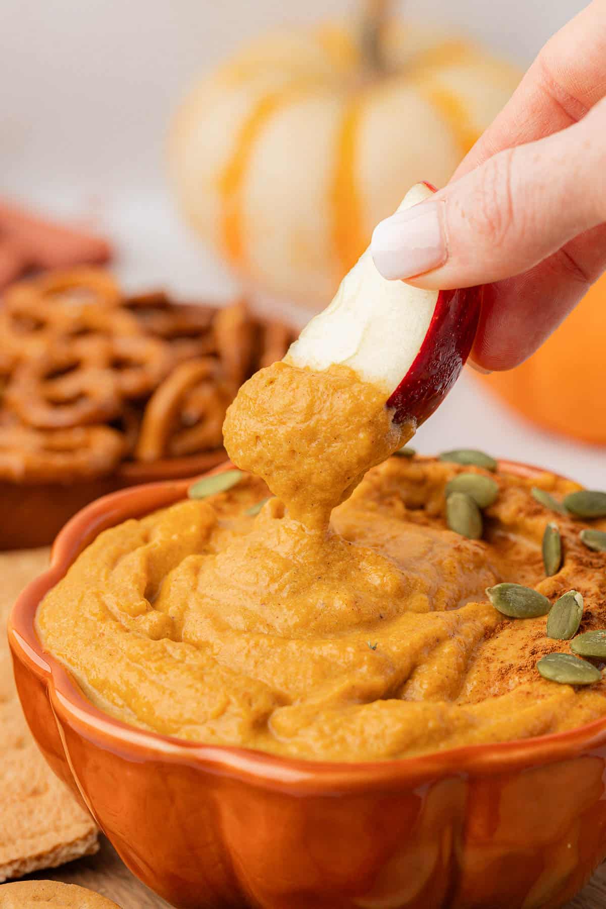 dipping an apple slice into pumpkin dip