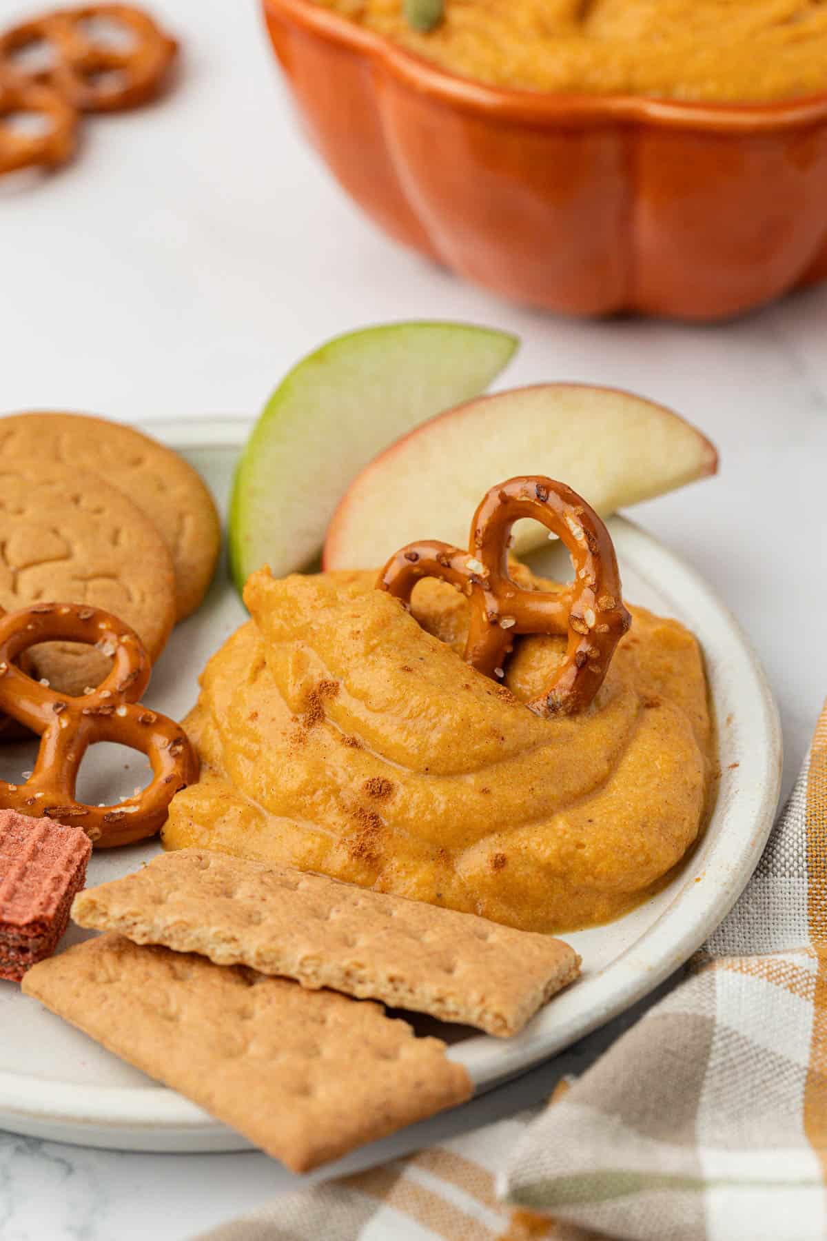 pretzel dipped in pumpkin dip on a plate