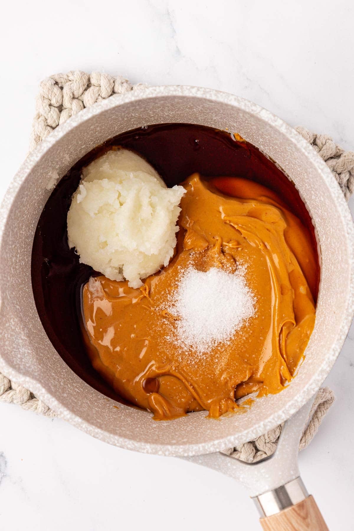 adding the peanut butter, maple syrup, coconut oil, and salt to a sauce pan