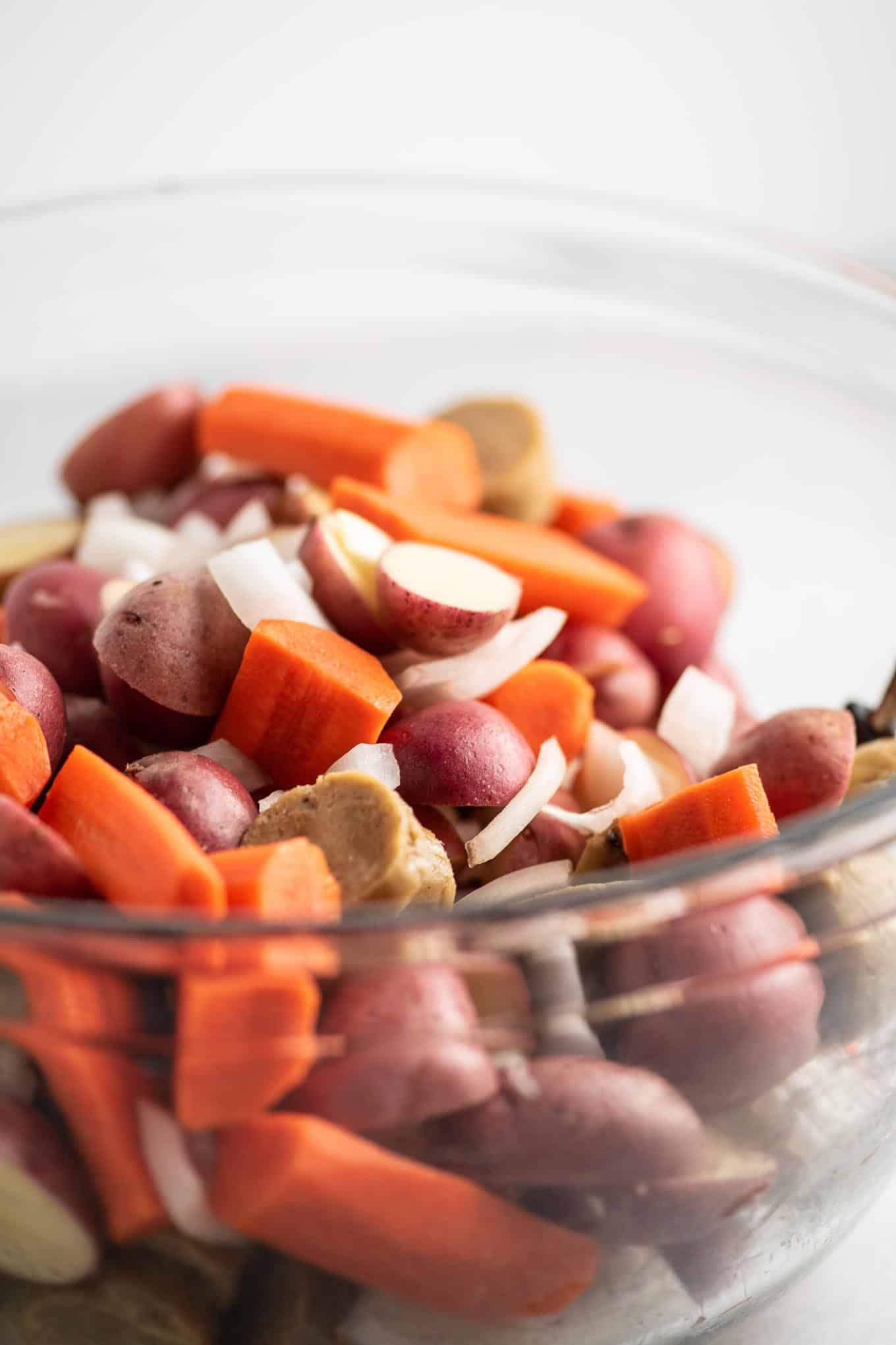 sliced potatoes, carrots, onions, and kielbasa in a bowl