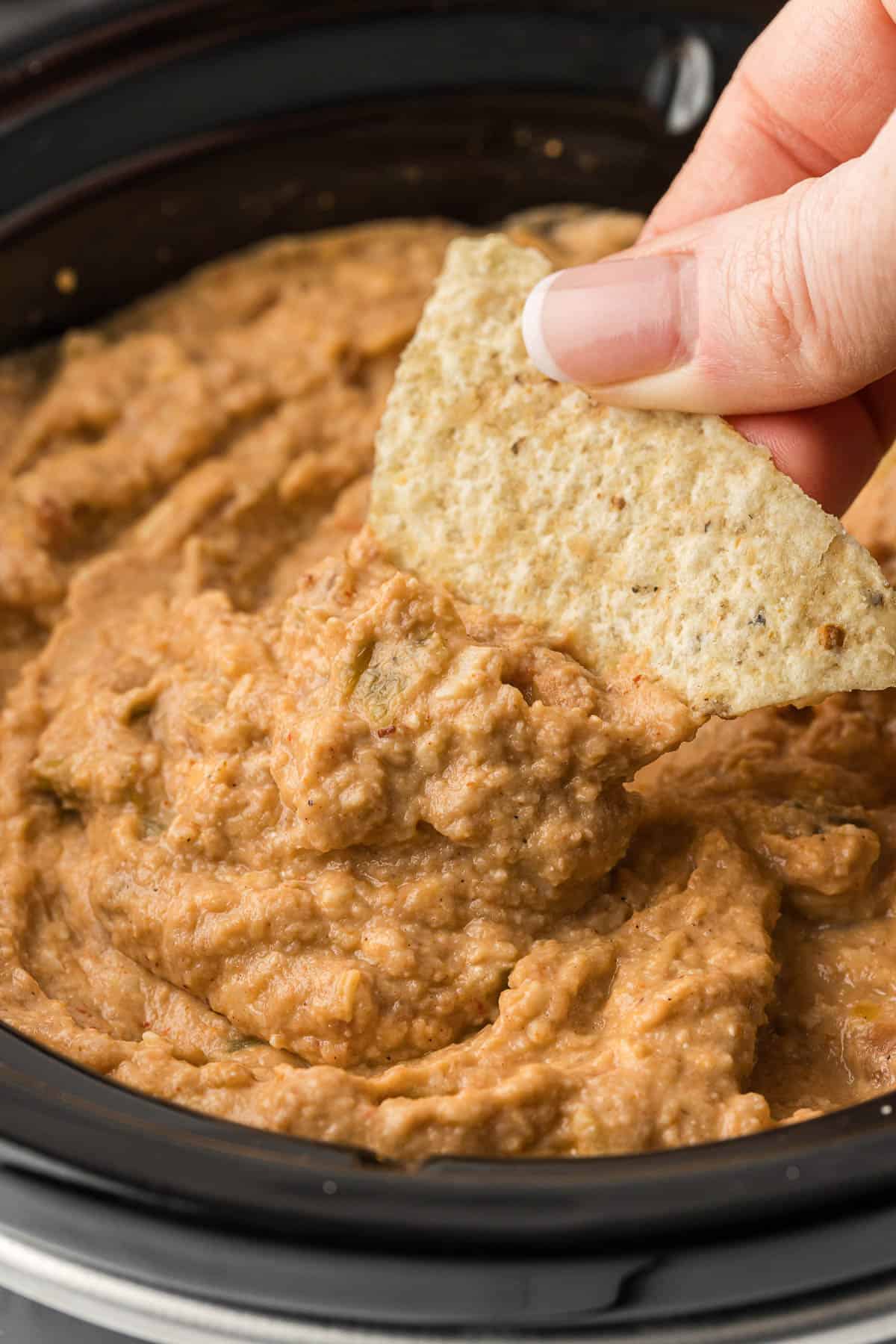dipping a tortilla chip into bean dip