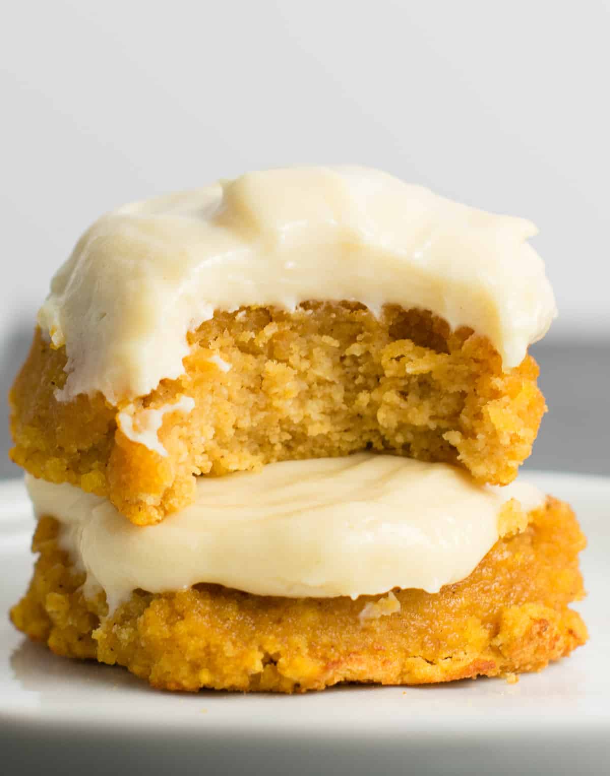 two pumpkin cookies stacked with the top one missing a bite