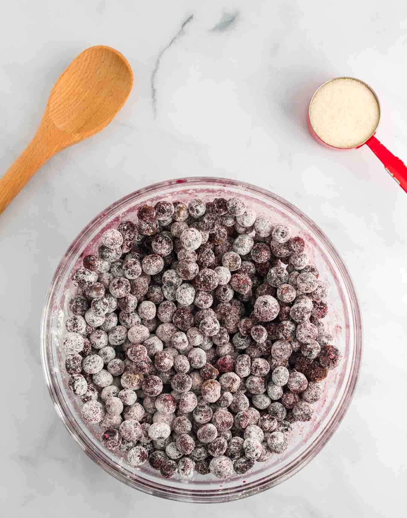 blueberries in a glass bowl mixed with cornstarch, sugar, and cinnamon