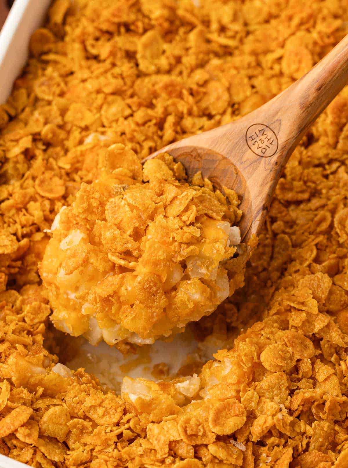 taking a scoop of funeral potatoes from the baking dish