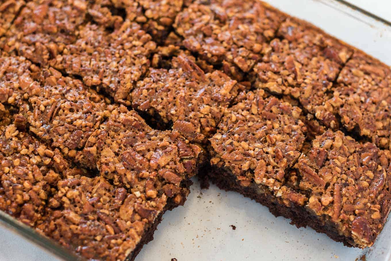cut up pecan pie brownies in a glass baking dish with 4 removed