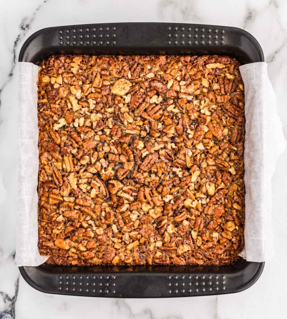 pecan pie bar filling poured over shortbread crust