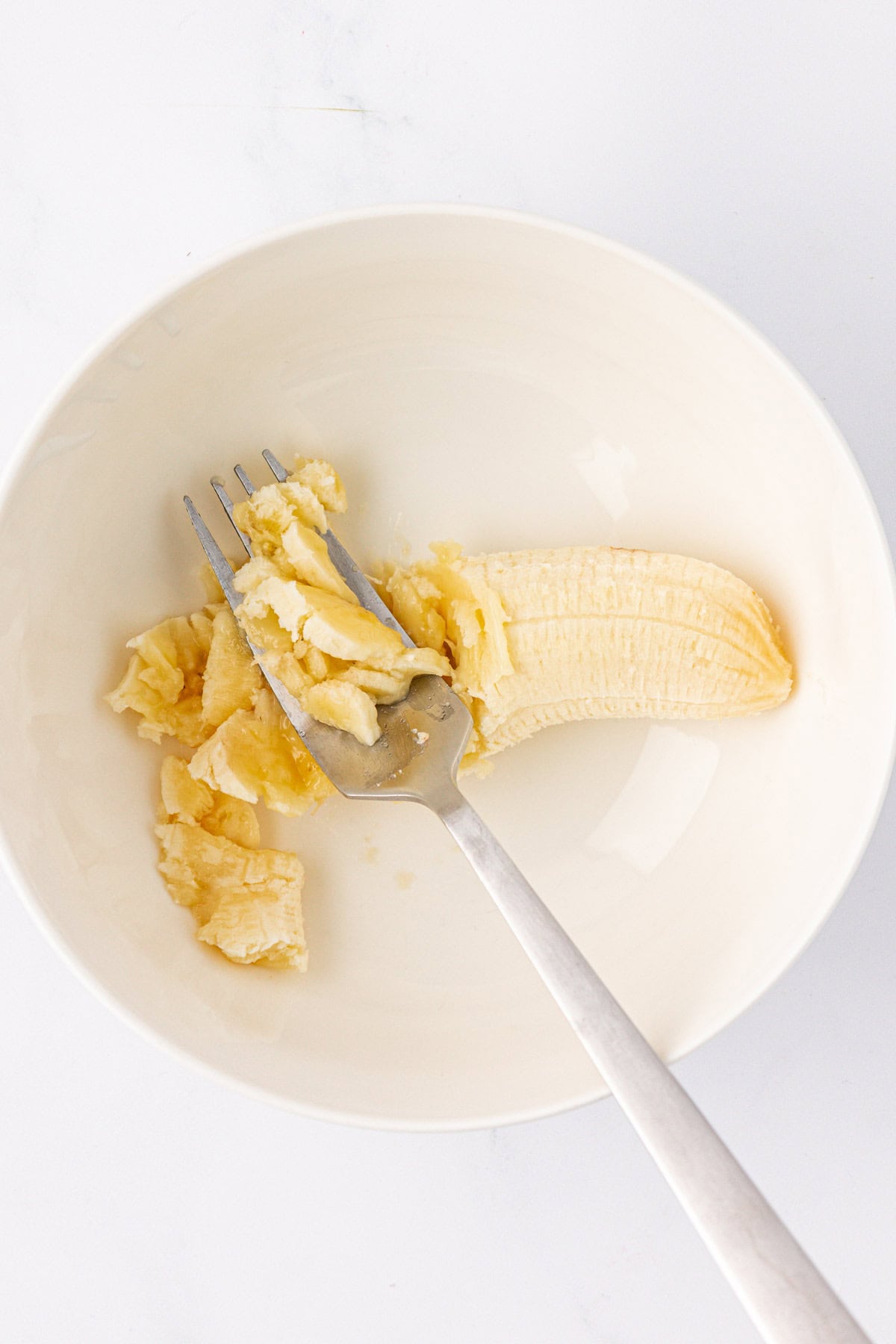 mashing a banana in a bowl with a fork
