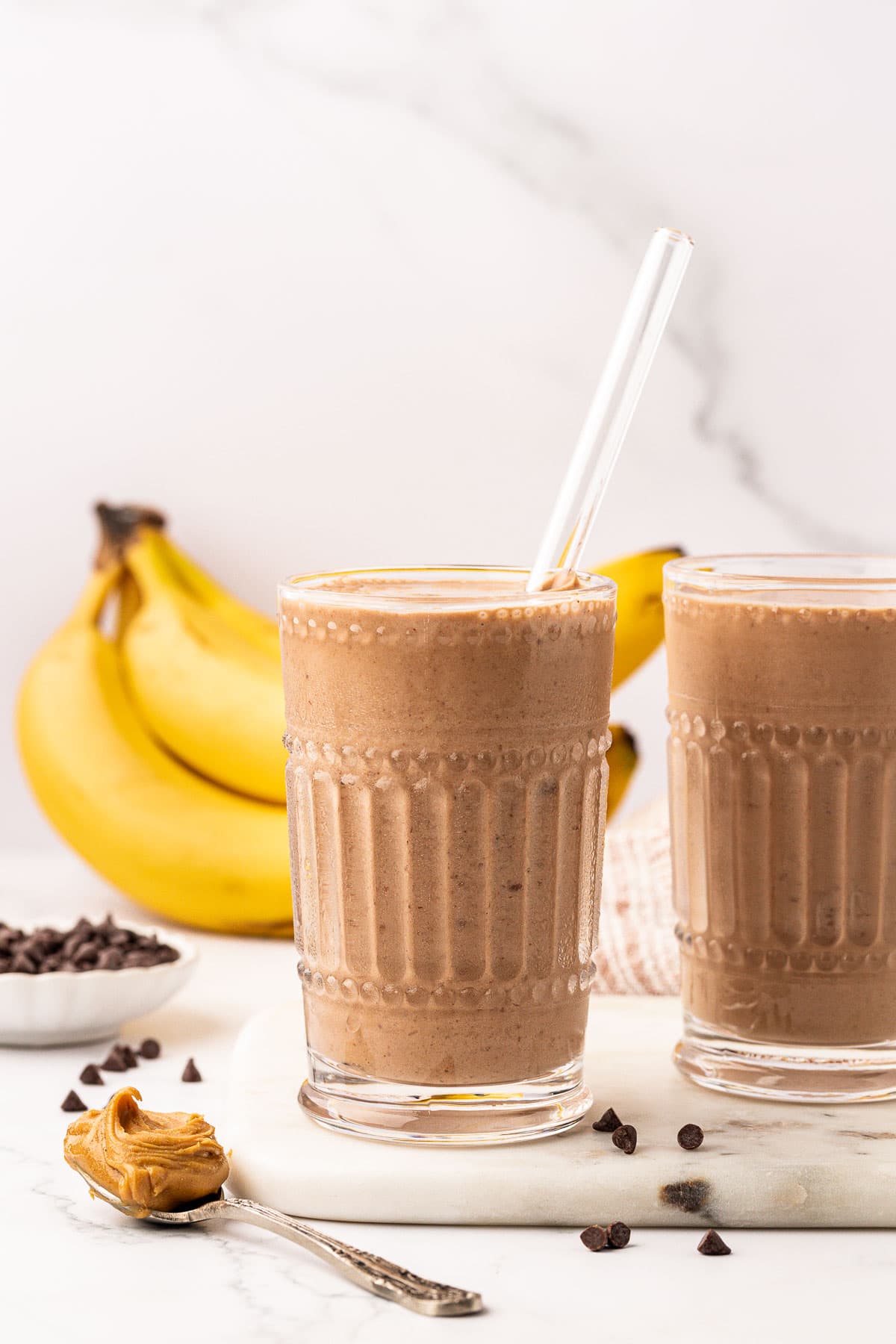 chocolate peanut butter banana smoothie in a glass with a straw