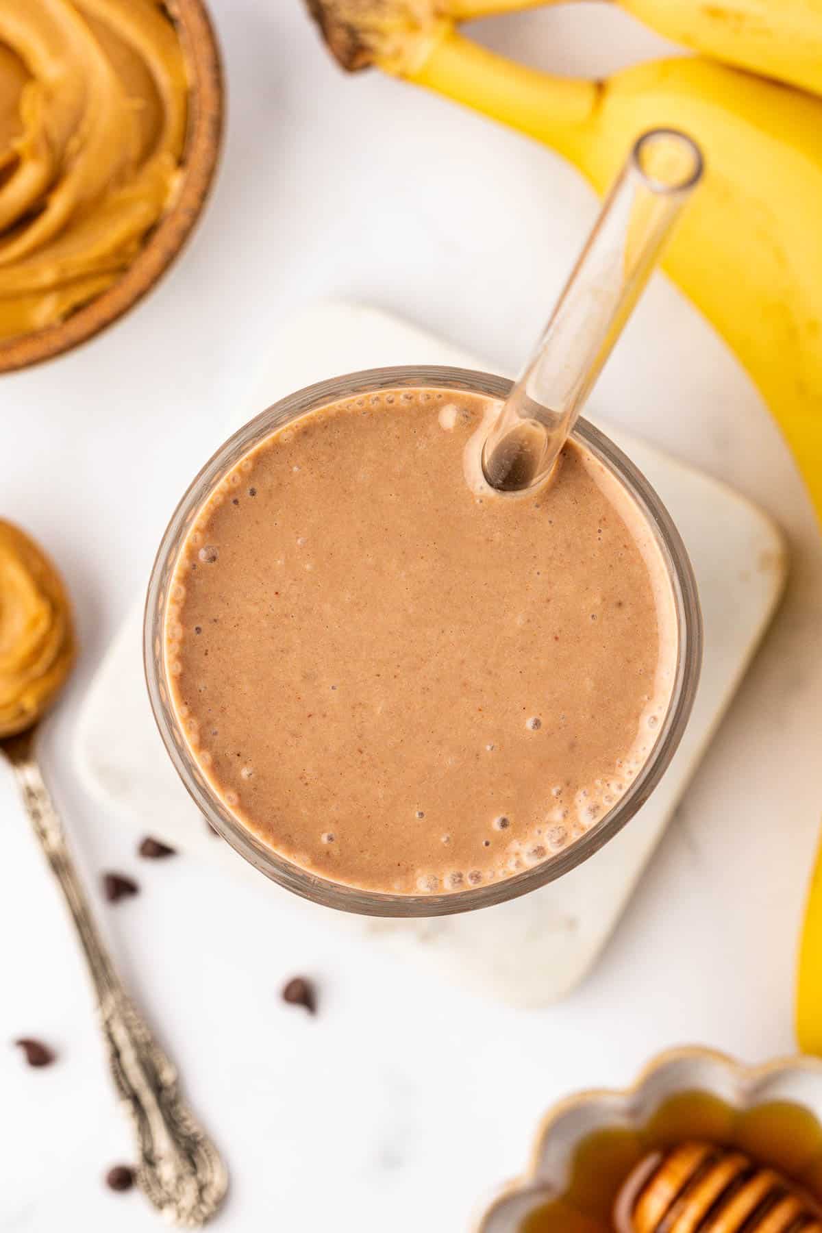 chocolate peanut butter banana smoothie in a glass with a straw