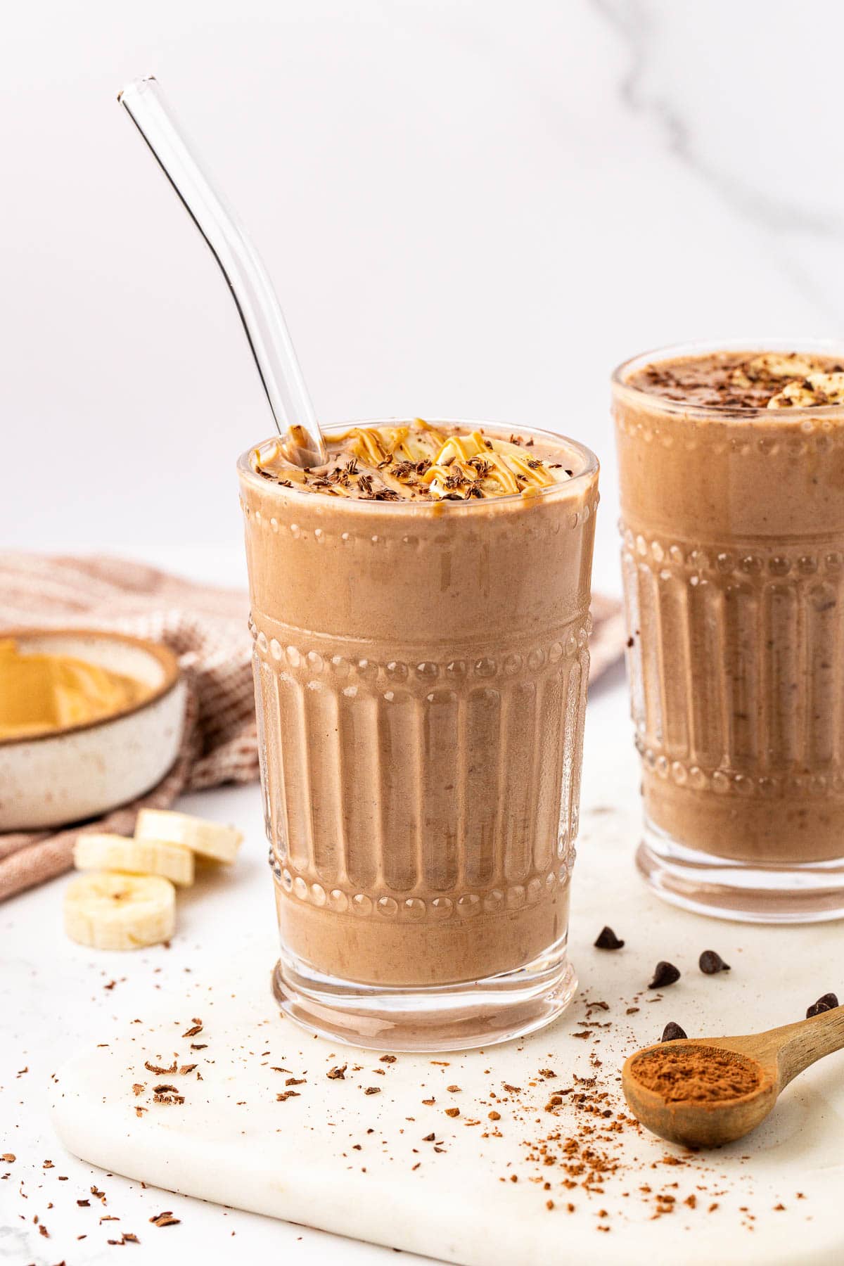 chocolate peanut butter banana smoothie in a glass with a straw