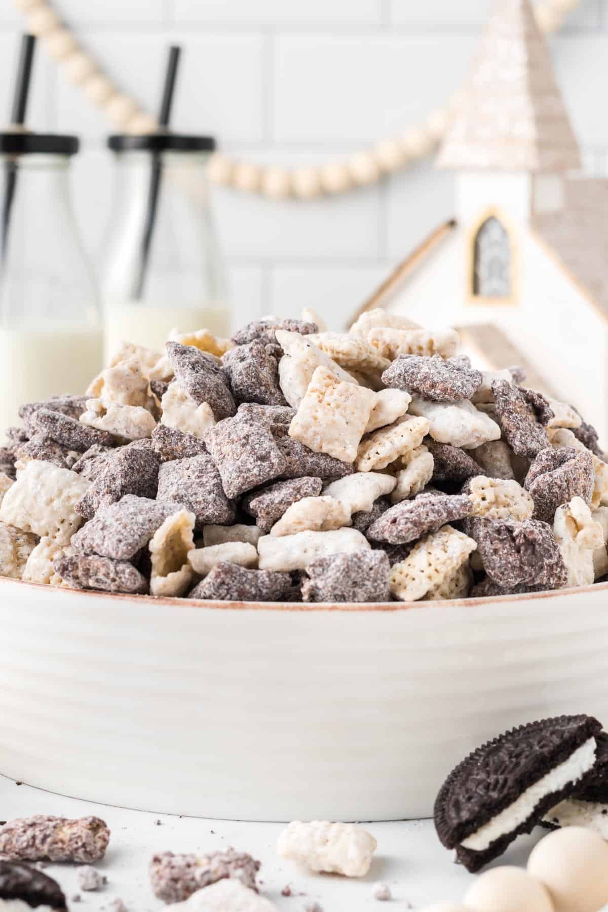 cookies and cream muddy buddies in a large serving bowl with Christmas decorations in the background