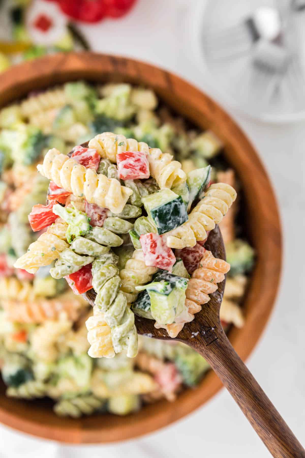 wooden spoon taking a scoop of pasta salad from the bowl