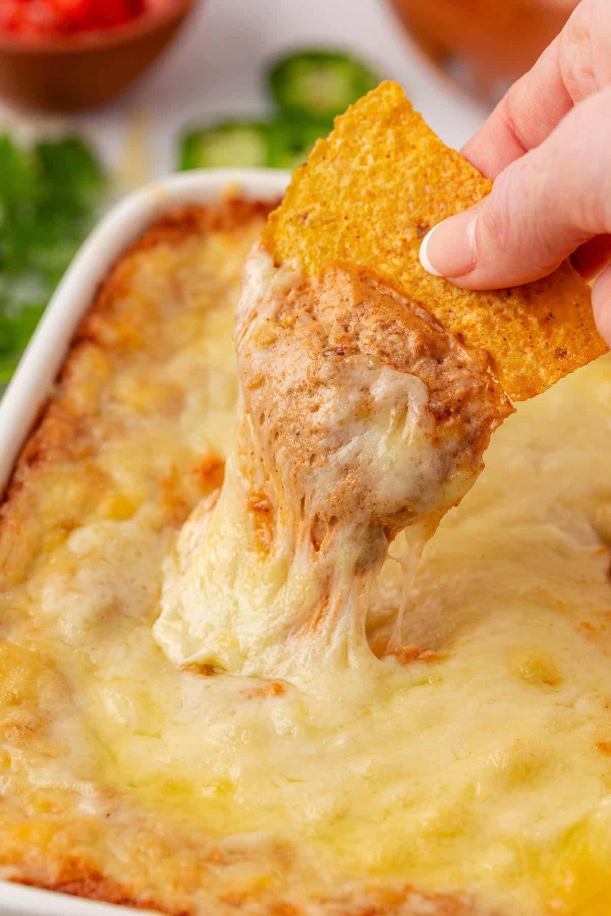 dipping a chip into cream cheese bean dip