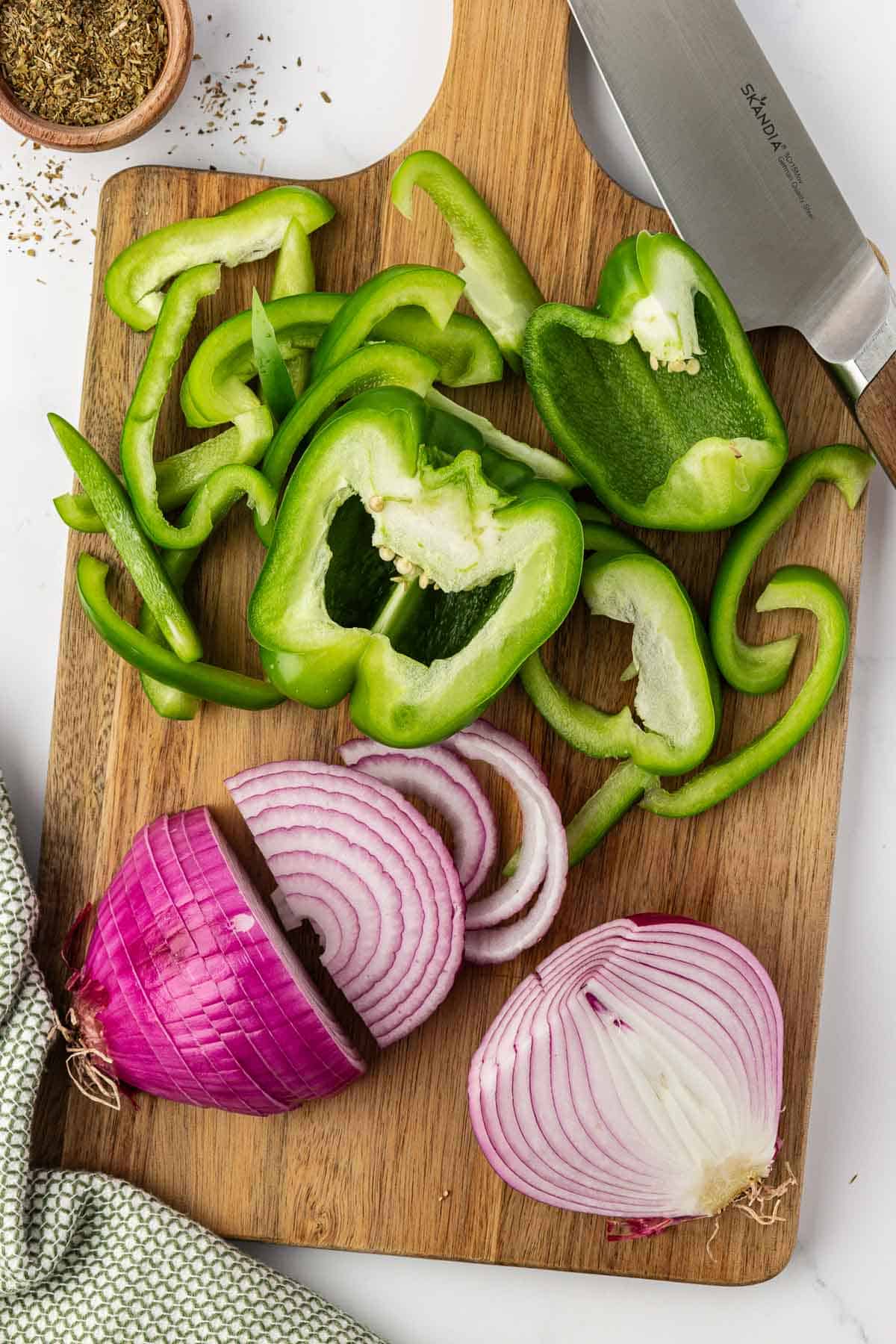cut up bell pepper and red onion on a cutting board