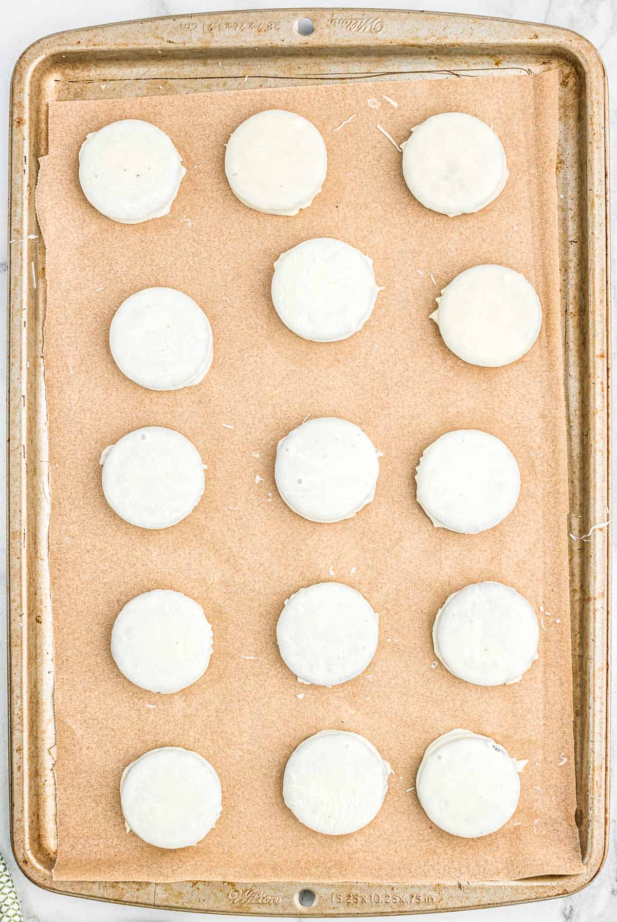 white chocolate coated Oreos on a lined baking sheet