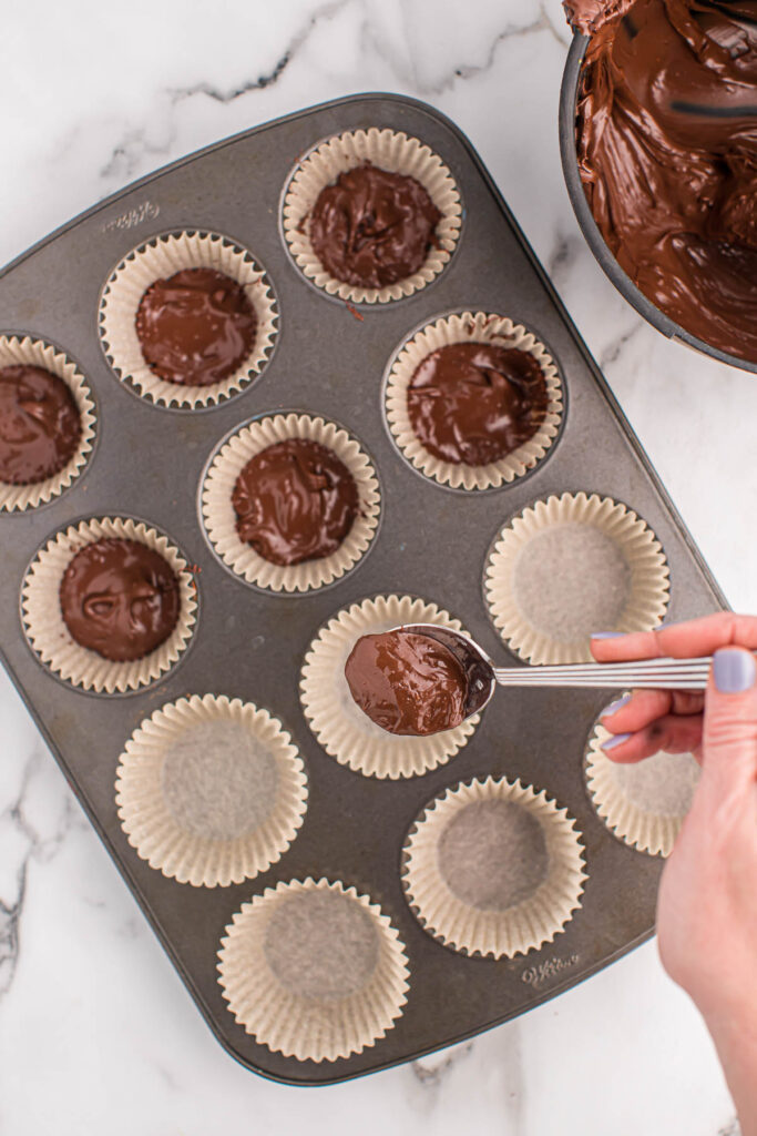 spooning melted chocolate into parchment paper muffin liners