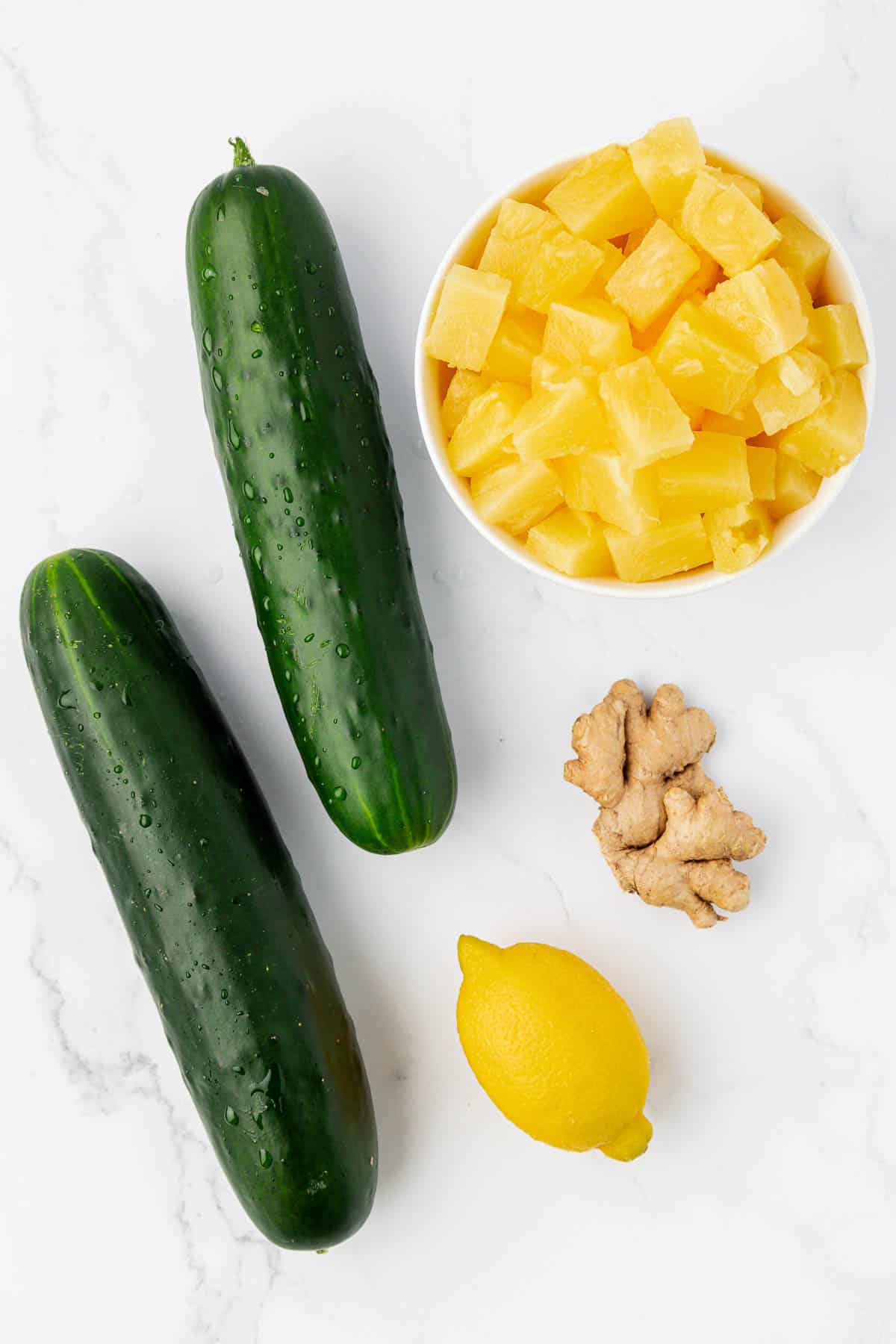 two cucumbers, lemon, pineapple chunks, and ginger