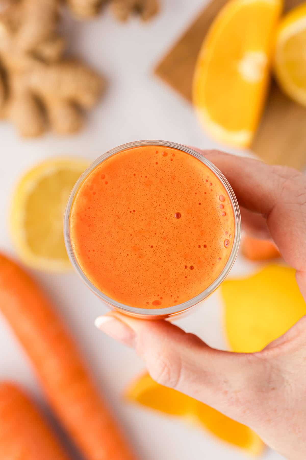 hand holding a glass of carrot orange juice