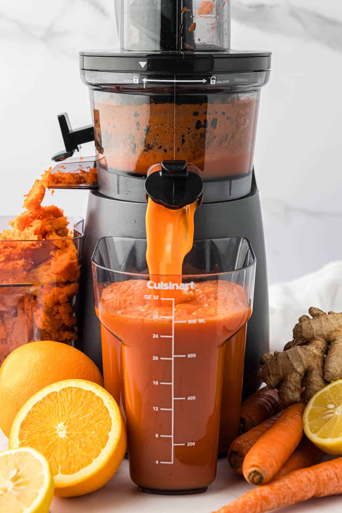 carrot orange juice pouring out of a juicer