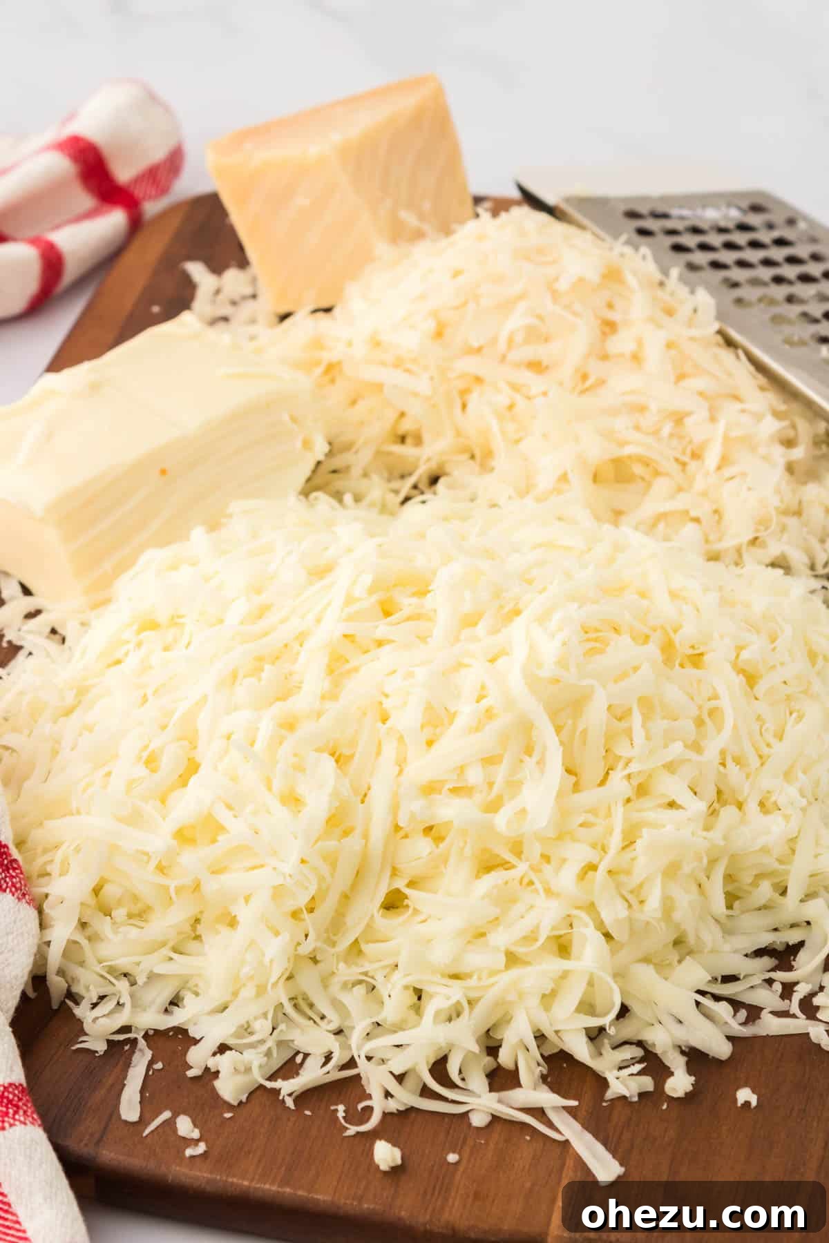 A close-up of various grated cheeses, including mozzarella and parmesan, ready for layering in the baked spaghetti.