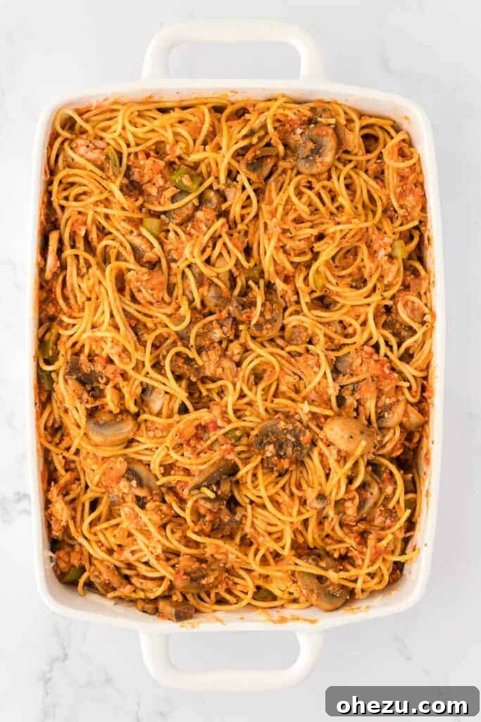 Spaghetti mixed thoroughly with sauce and vegetables in the casserole dish.
