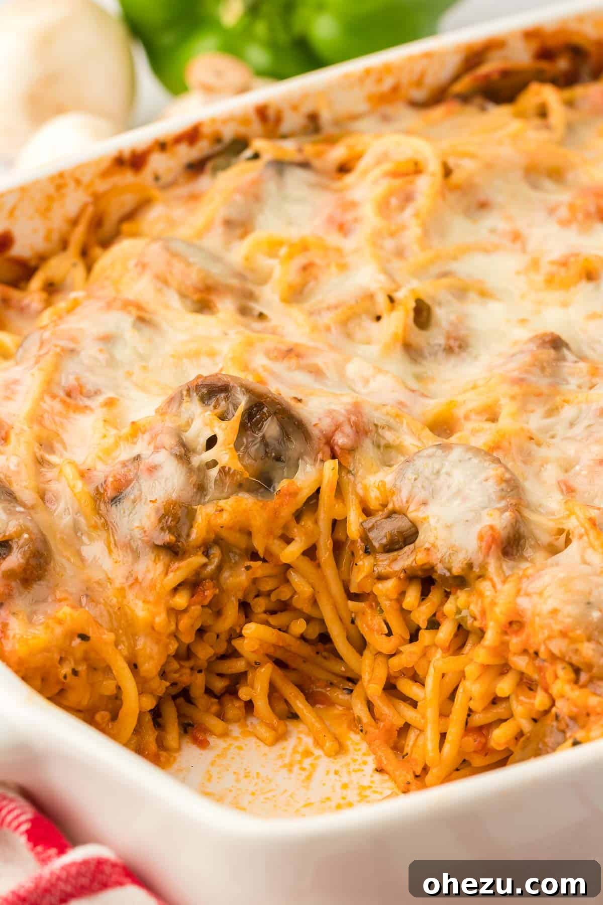 A wide shot of the baked veggie spaghetti in a casserole dish, garnished with fresh herbs, ready to be served.