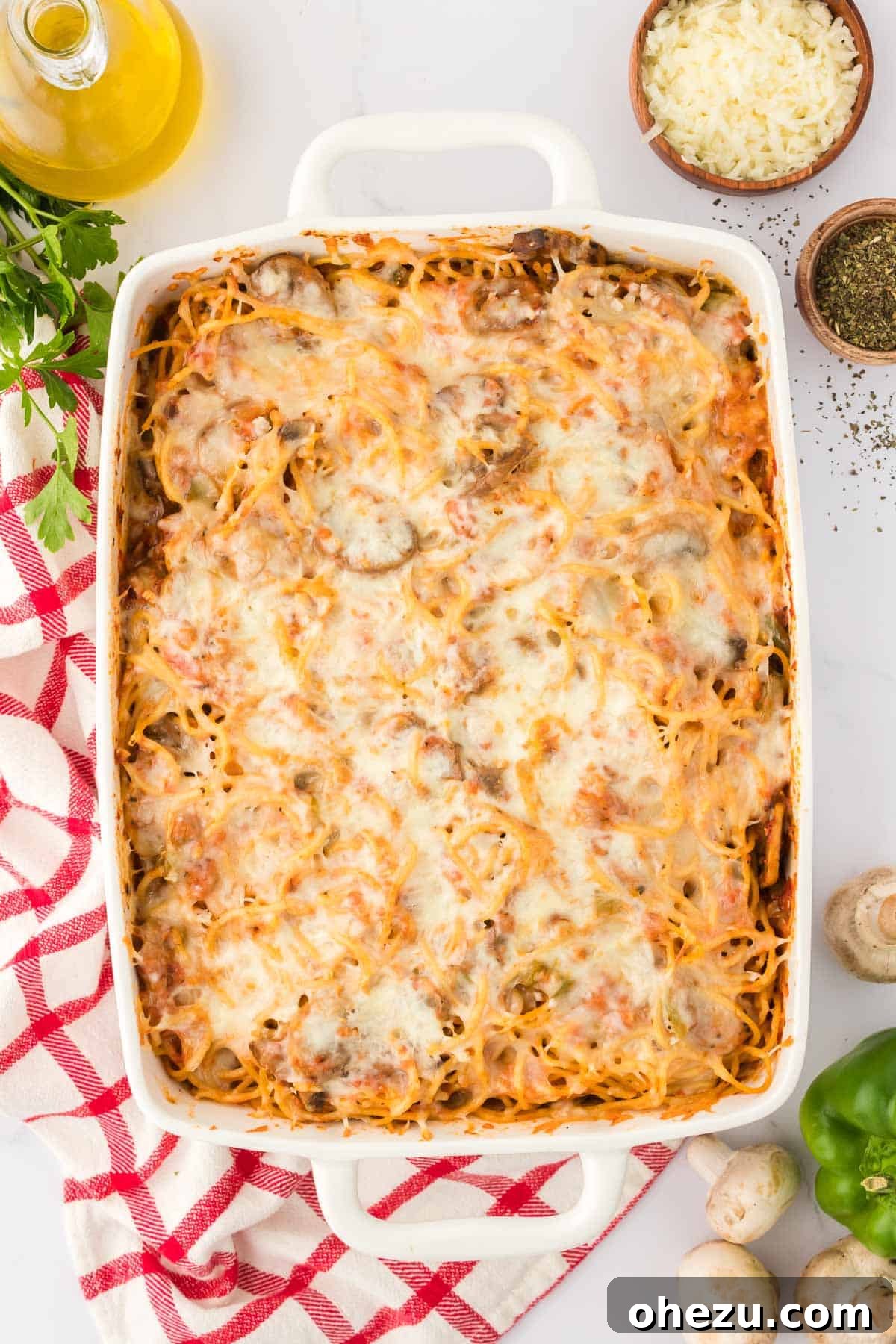 Close-up shot of vegetarian baked spaghetti in a white casserole dish, showing the cheesy topping and savory sauce.