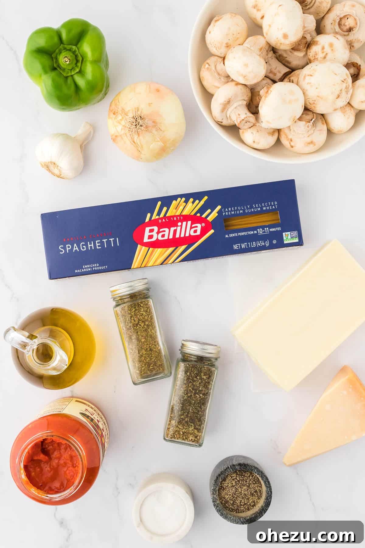 A selection of fresh ingredients laid out on a wooden cutting board, including mushrooms, onion, bell pepper, and garlic, ready to be prepared for the veggie spaghetti bake.
