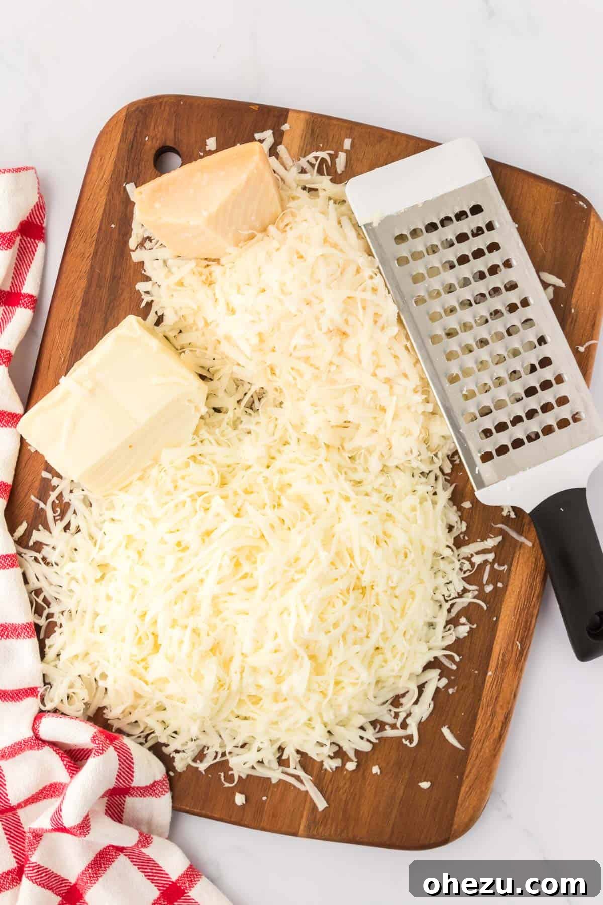 A close-up of freshly grated cheese piled on a wooden cutting board, ready for use in the baked spaghetti.