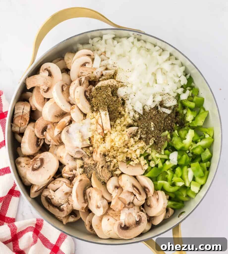 Assorted vegetables including mushrooms, onions, and bell peppers cooking in a skillet with spices.