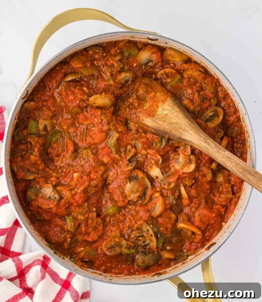 Vegetarian pasta sauce mixed with a colorful array of cooked vegetables in a skillet.