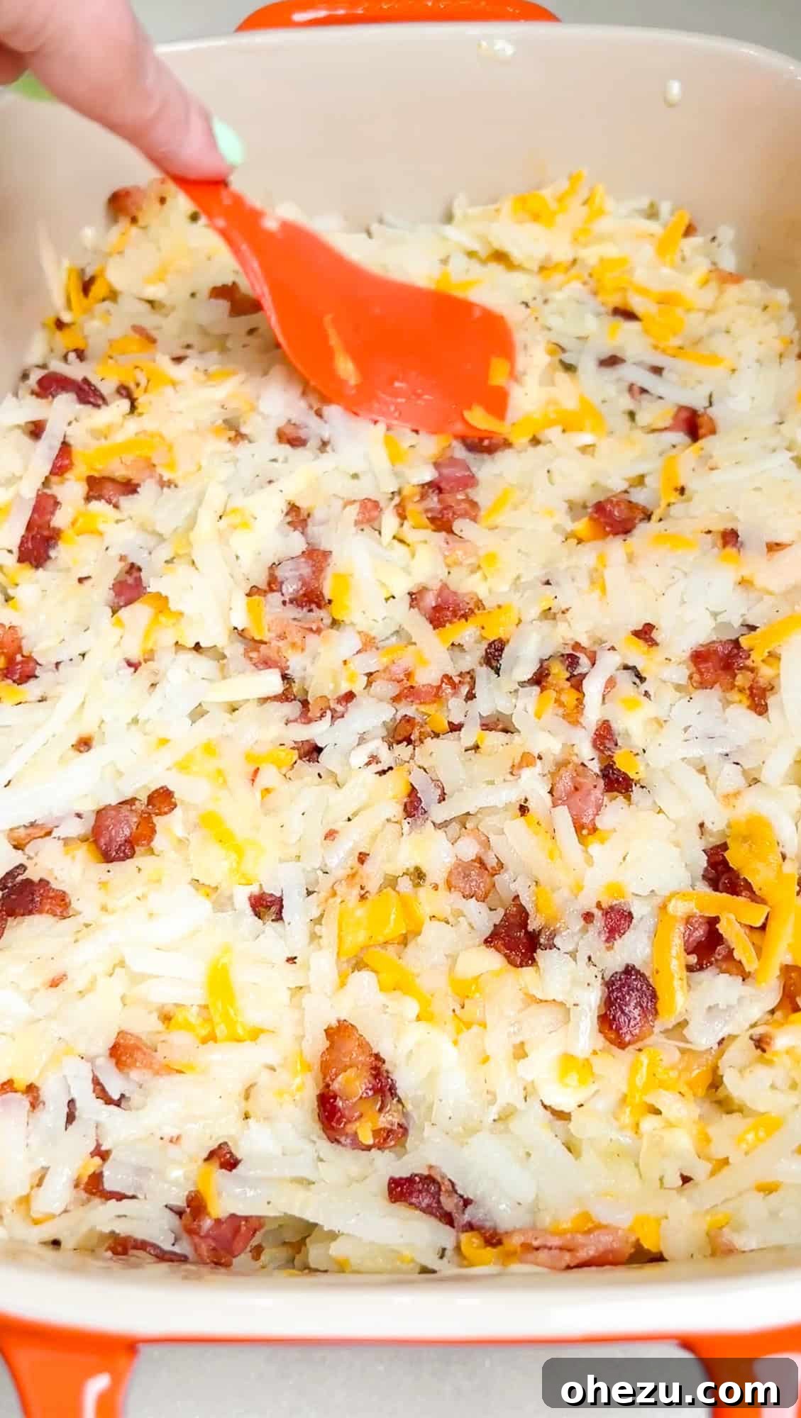 Mixing shredded cheeses and diced bacon with par-baked hashbrowns