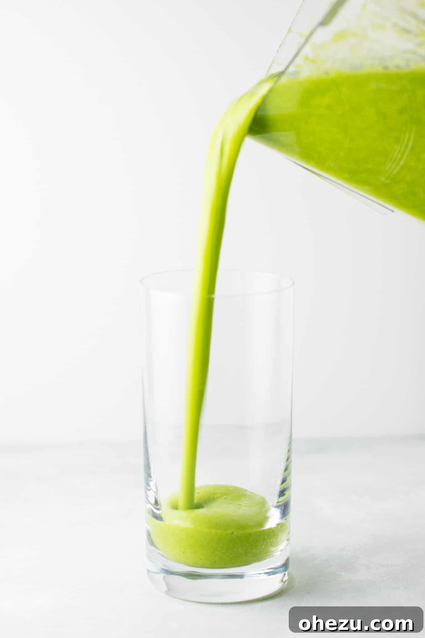 A final glass of green smoothie, made with kale, ginger, oranges, lemon, frozen banana, peaches, and water, ready to drink
