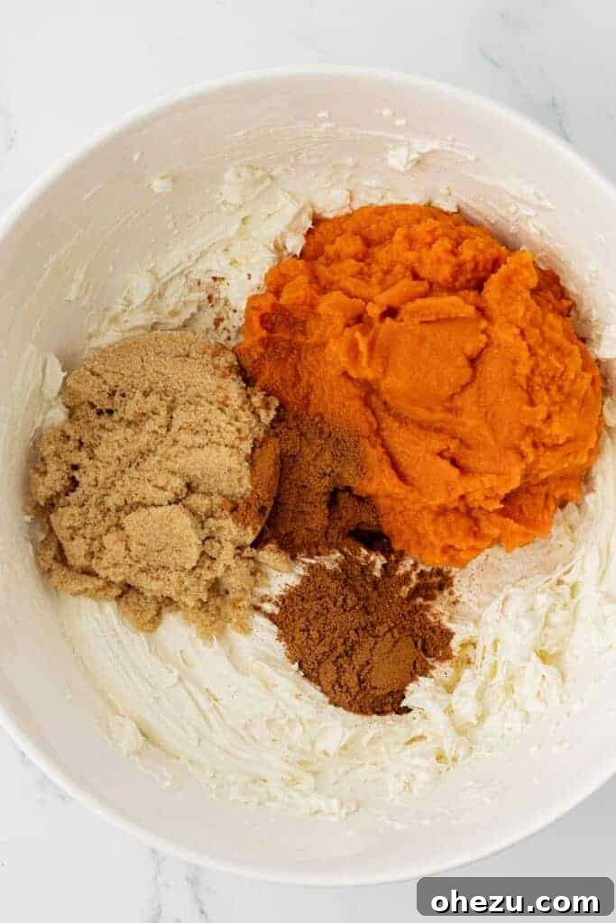 Adding pumpkin puree, spices, and brown sugar into the whipped cream cheese in a mixing bowl