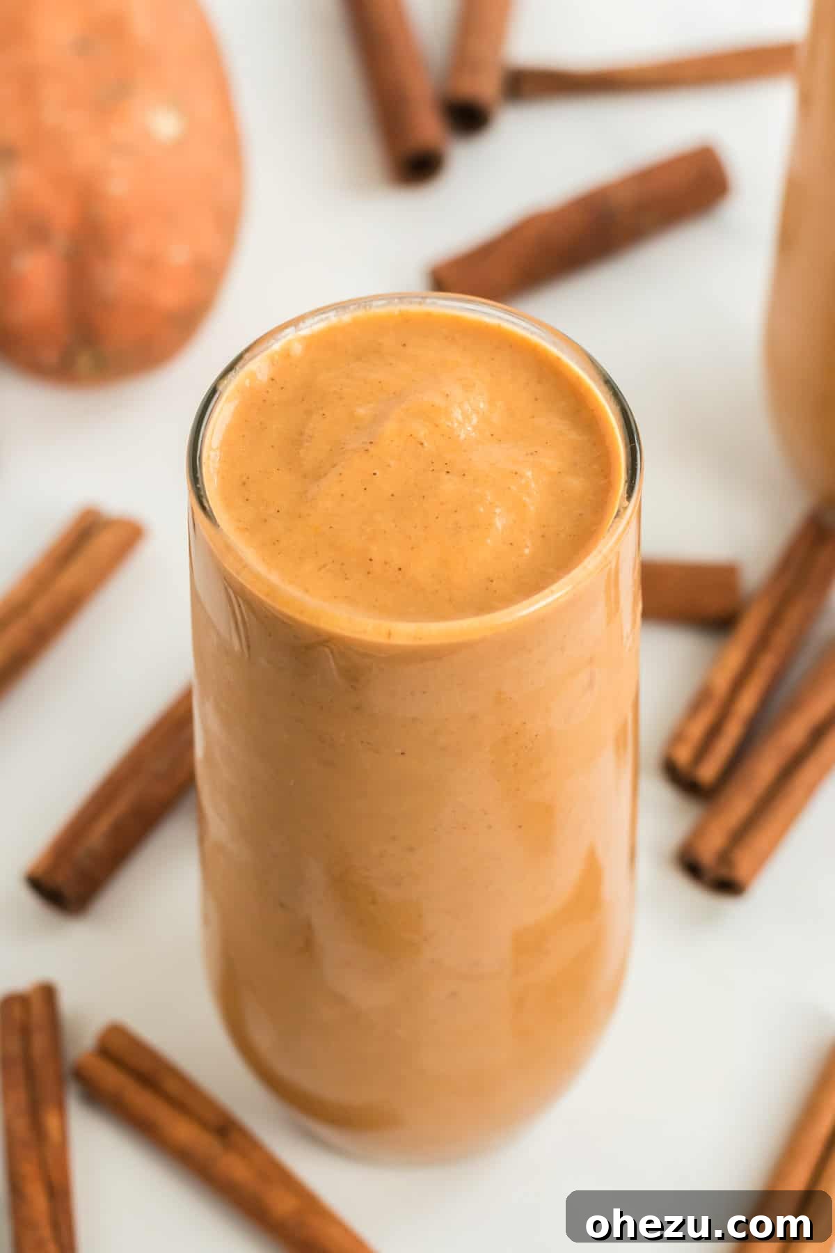 Wholesome Sweet Potato Bliss 11 tall glass filled with sweet potato smoothie with cinnamon sticks in the background