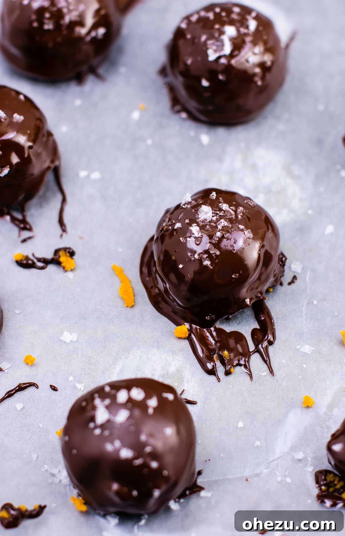 Freshly dipped pumpkin truffles in melted chocolate, waiting to be garnished.
