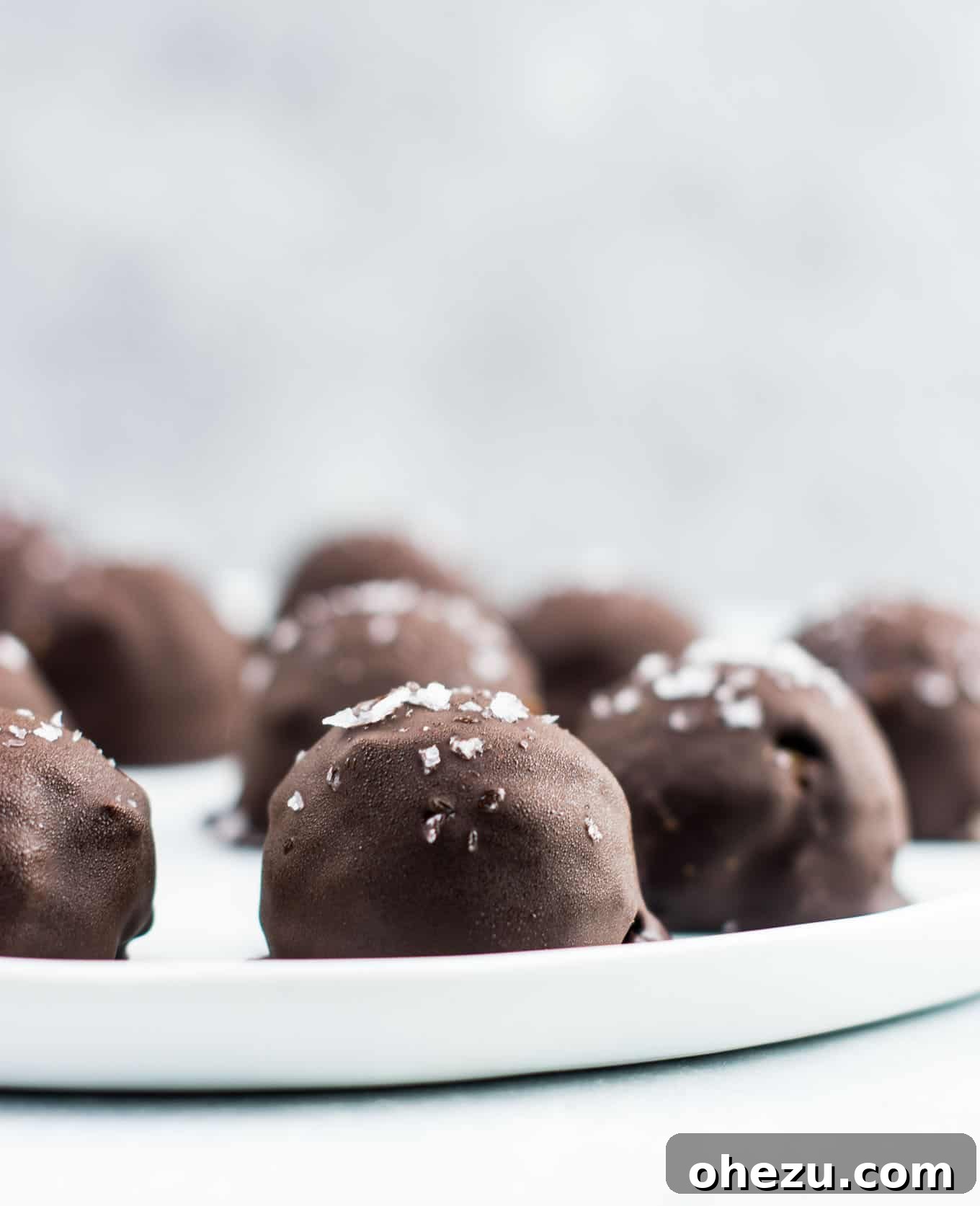 A cluster of dark chocolate pumpkin truffles on a white plate, showcasing their inviting appearance.