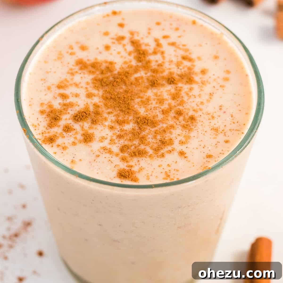 Glass full of healthy apple pie smoothie topped with a sprinkle of cinnamon, ready to be enjoyed.