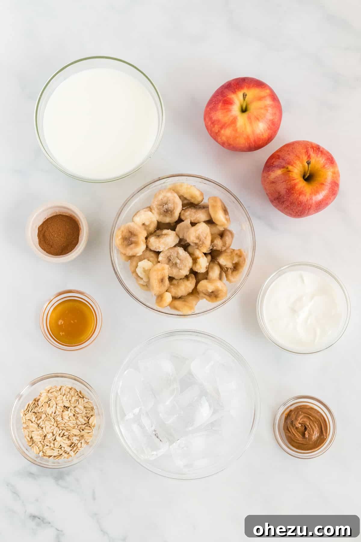 All the fresh ingredients meticulously laid out to make a healthy apple pie smoothie, including apples, bananas, oats, and cinnamon.