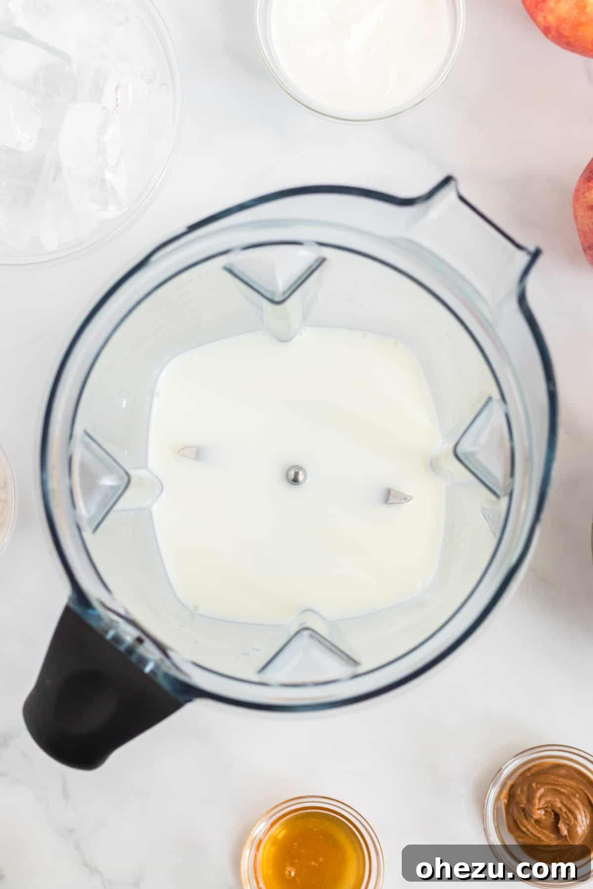 A high-speed blender container with a base layer of milk, ready for the next ingredients.