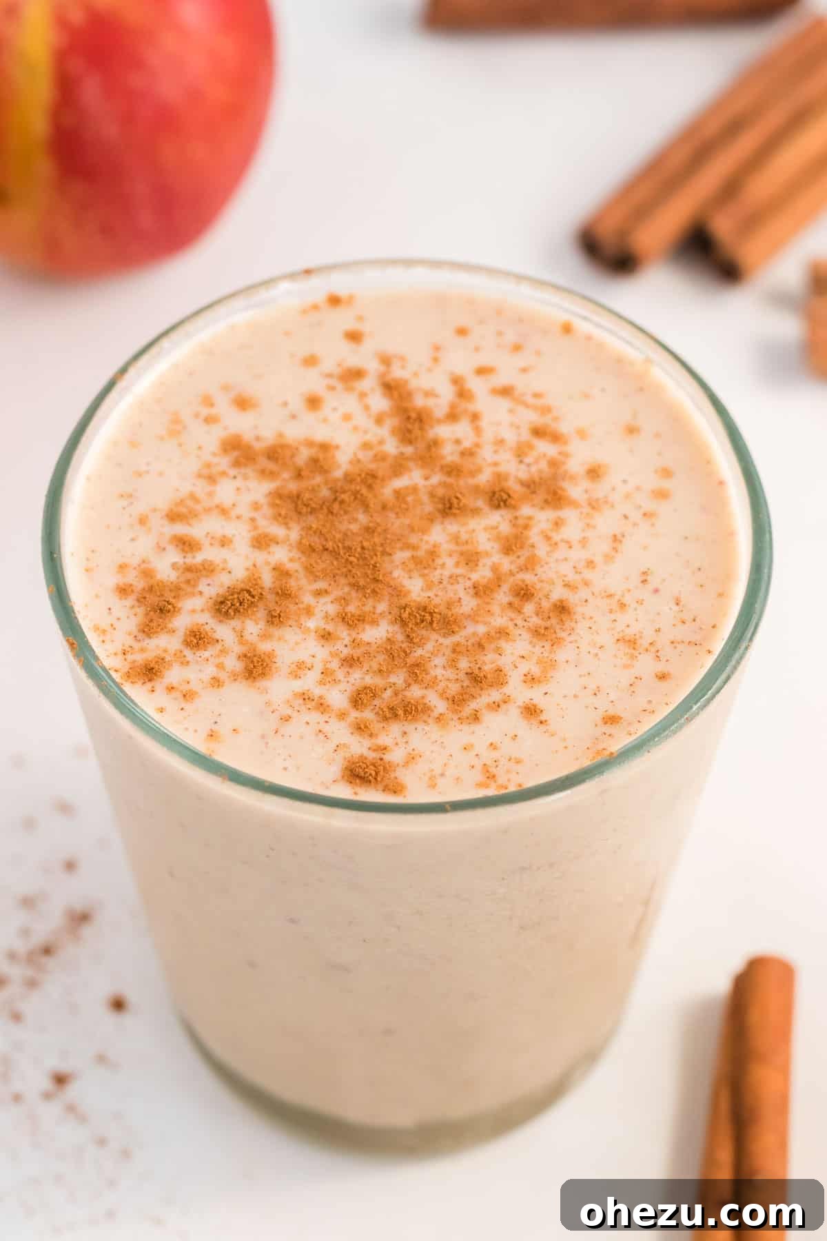 A glass brimming with healthy apple pie smoothie, elegantly topped with a dusting of cinnamon.