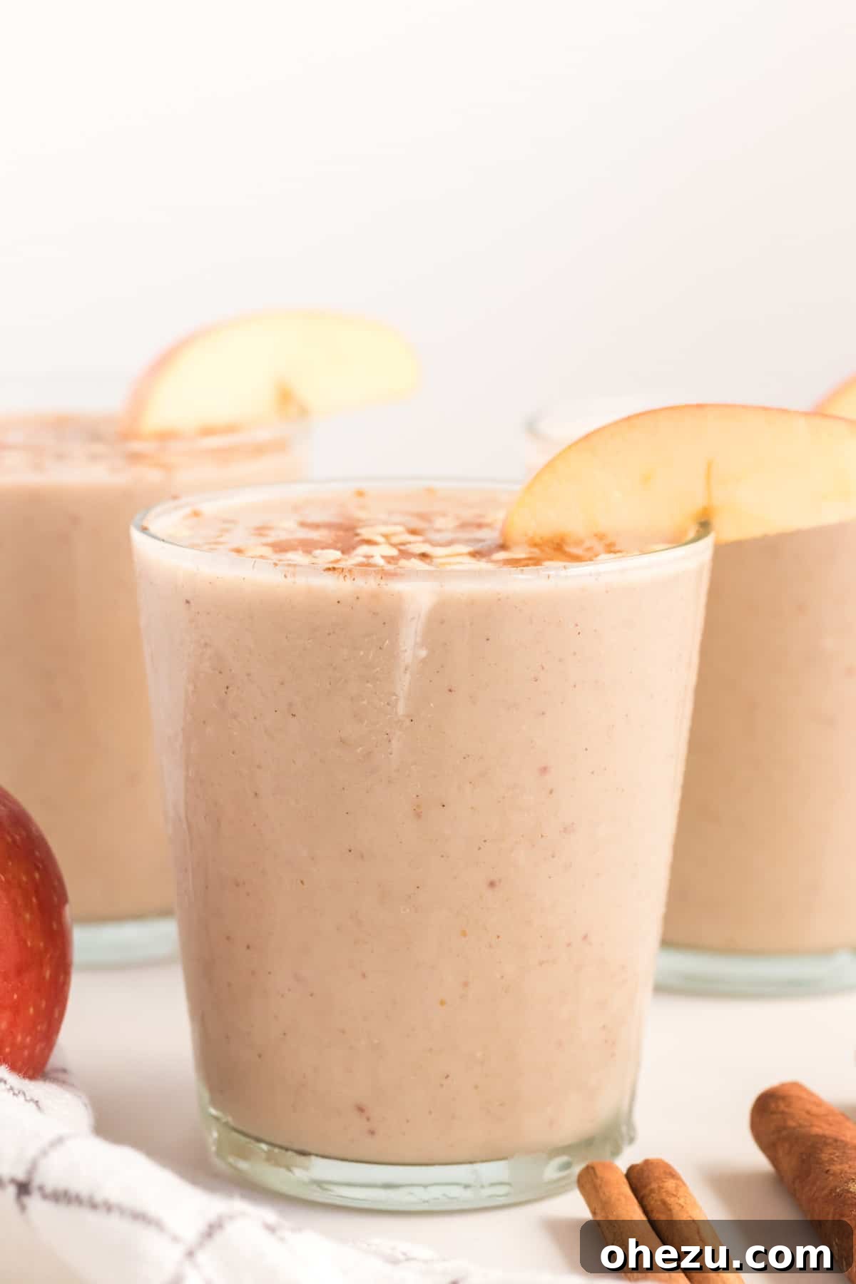 A close-up of a glass of healthy apple pie smoothie, garnished with cinnamon and rolled oats for an extra touch of texture and flavor.