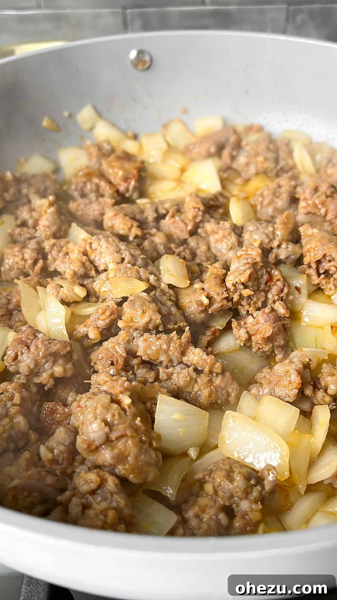 Hearty Creamy Sausage Alfredo Bake 6 cooking sausage and onions in a skillet