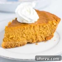 A perfect slice of gluten-free pumpkin pie on a white plate, elegantly topped with a swirl of whipped cream, ready for a festive celebration.