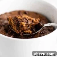 A fluffy and decadent gluten-free chocolate mug cake, topped with a scoop of vanilla ice cream, served in a mug. Made with easy-to-find flours, it's a perfect single-serving dessert.