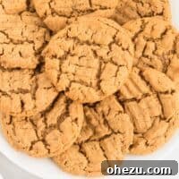 A simple white plate featuring a batch of perfectly baked gluten-free peanut butter cookies, showcasing their classic crosshatch pattern.
