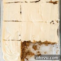 A delectable gluten-free carrot cake with two slices already removed, revealing its moist interior and generous cream cheese frosting. It's a classic dessert made accessible for gluten-free diets.